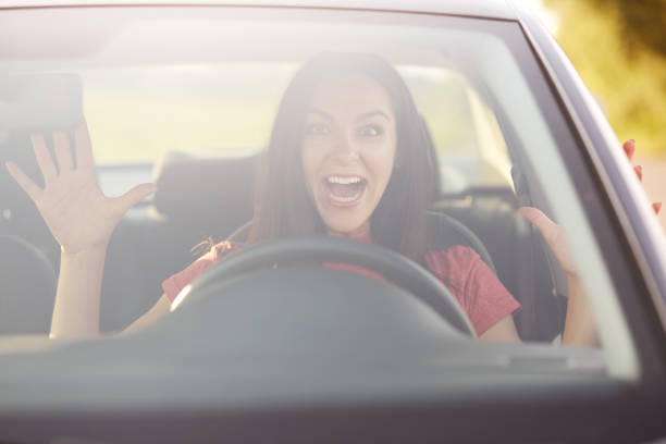 istock Emotions, driving and speed concept. Surprised female driver gestures with both hands, likes risk, takes off hands from wheel while drives car, has glad and shocked expression, enjoys speed on road 1043135188