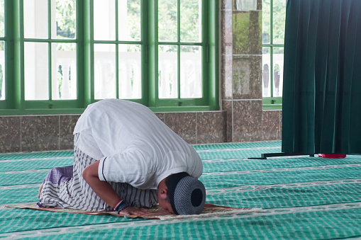Banjar City, Indonesia - Feb 23, 2024: Asian Muslim men are sitting in the mosque waiting for prayer time to arrive.