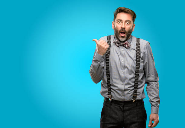 istock Middle age man, with beard and bow tie happy and surprised cheering expressing wow gesture pointing up 1043146896