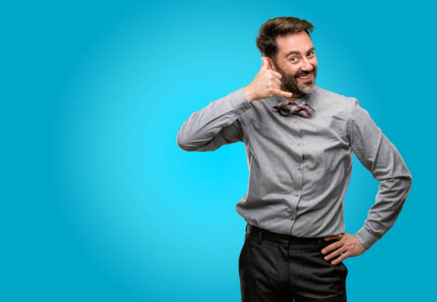 istock Middle age man, with beard and bow tie happy and excited making showing call me gesture with hand shaped like telephone 1043147898
