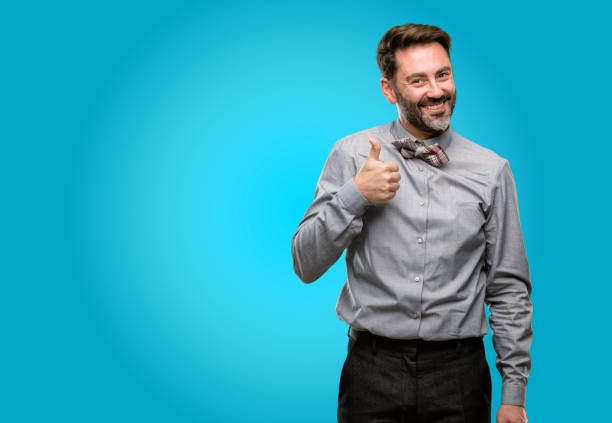 istock Middle age man, with beard and bow tie smiling broadly showing thumbs up gesture to camera, expression of like and approval 1043147902