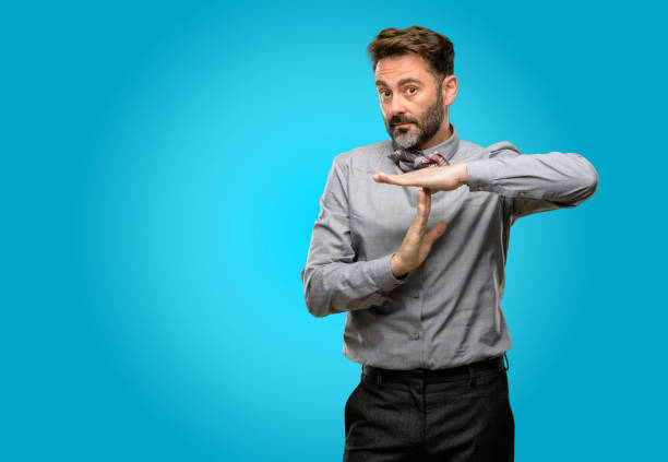 istock Middle age man, with beard and bow tie serious making a time out gesture with hands 1043148082