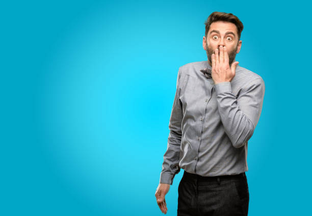 istock Middle age man, with beard and bow tie covers mouth in shock, looks shy, expressing silence and mistake concepts, scared 1043152604