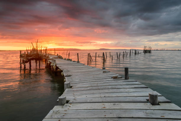 Sunset landscape of artisanal fishing boats in the old wooden pier Sunset landscape of artisanal fishing boats in the old wooden pier. Carrasqueira is a tourist destination for visitors to the coast of Alentejo near Lisbon. troia stock pictures, royalty-free photos & images