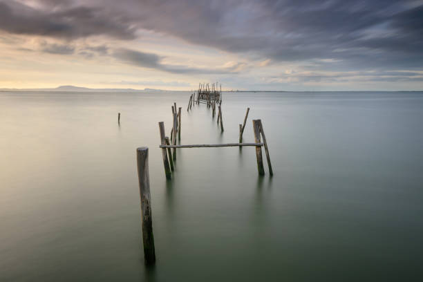 Sunset landscape of artisanal fishing boats in the old wooden pier Sunset landscape of artisanal fishing boats in the old wooden pier. Carrasqueira is a tourist destination for visitors to the coast of Alentejo near Lisbon. troia stock pictures, royalty-free photos & images