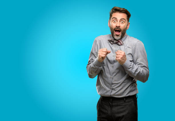 istock Middle age man, with beard and bow tie happy and surprised cheering expressing wow gesture 1043152708