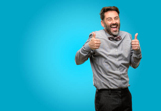 istock Middle age man, with beard and bow tie smiling broadly showing thumbs up gesture to camera, expression of like and approval 1043152824