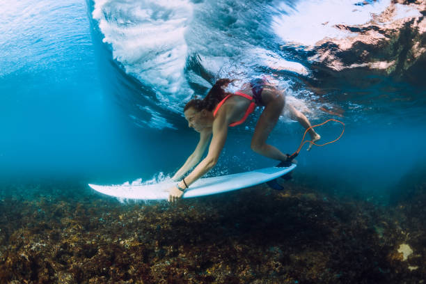 istock Professional surfer woman with surfboard dive underwater with ocean wave. 1043154108