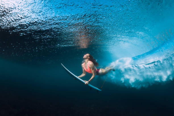 istock Professional surfer woman with surfboard dive underwater with under big ocean wave. 1043154210
