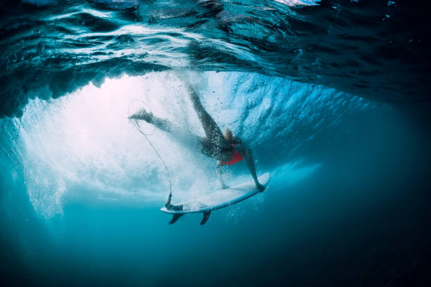 istock Surfer woman with surfboard dive underwater with under big ocean wave. 1043156300