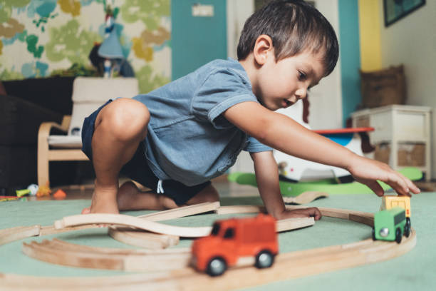 schattige kleine jongen spelen met houten trein - speelgoedauto stockfoto's en -beelden