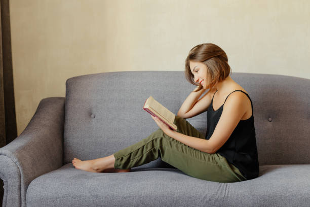 istock Young woman sitting on the sofa and reading a book 1043165384