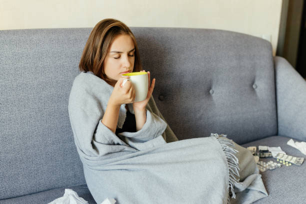 istock Woman feeling sick and drinking hot drink, at home 1043165580