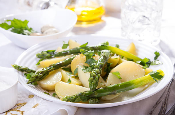 istock Boiled potato with grilled green asparagus on white plate over on white background. 1043169064