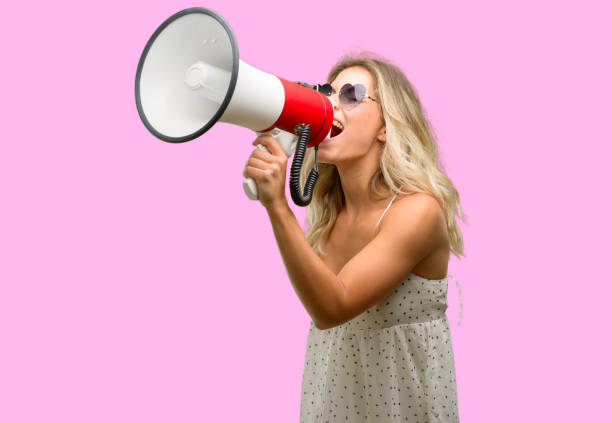istock Young woman wearing sunglasses with heart shape communicates shouting loud holding a megaphone, expressing success and positive concept, idea for marketing or sales 1043169270