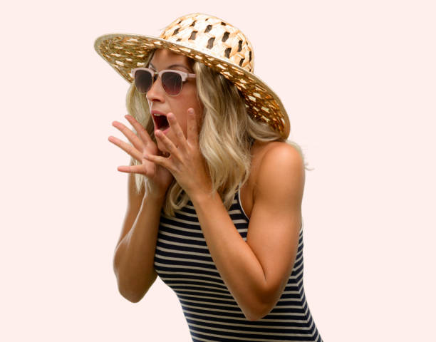 istock Young woman using sunglasses wearing summer hat stressful keeping hands on head, terrified in panic, shouting 1043169324
