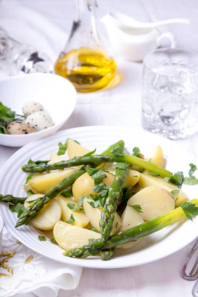 istock Boiled potato with grilled green asparagus on white plate over on white background. 1043169348