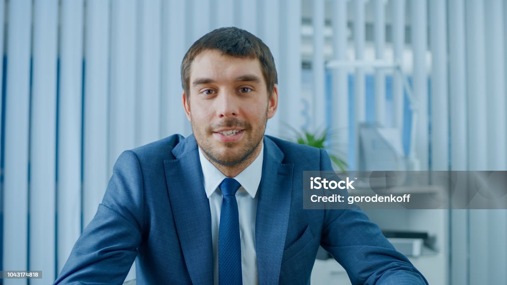 Handsome Respectable Businessman Sitting at His Desk in Office, Looking into the Camera. Discussion Stock Photo