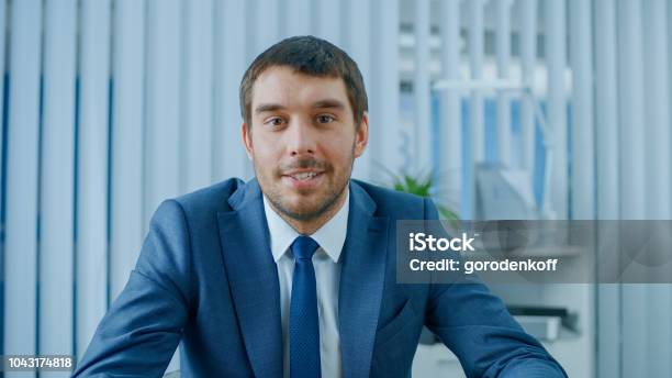 Handsome Respectable Businessman Sitting At His Desk In Office Looking Into The Camera Stock Photo - Download Image Now