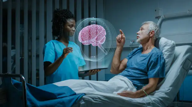 In the Hospital, Senior Patient Lying in the Bed Nurse Holding Tablet Computer Shows Augmented Reality Brain Scan. They Both Make Gestures and Talk. In the Technologically Advanced Hospital Ward.