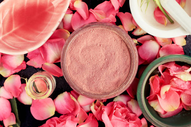istock Pink cosmetic clay closeup with rose petals, ceramic bowls on black table 1043174954