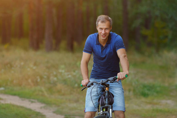istock Young man rides on bicycle in pine forest looking at camera. 1043178458