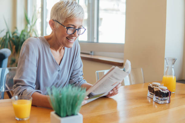 istock Older woman reading newspapers and smiling 1043179594