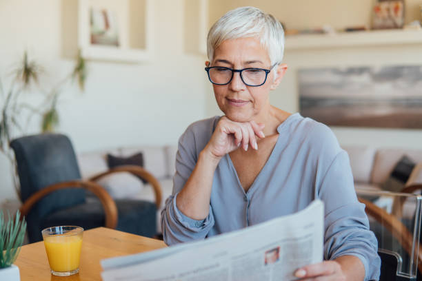 istock Older woman reading newspapers 1043179600