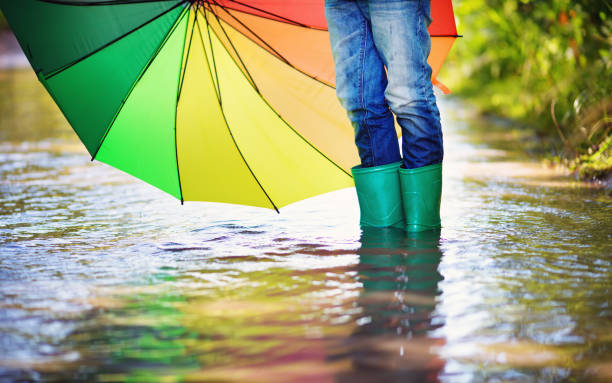 Young girl wearing yellow rain boots walking on wet street paving stone floor. Santiago de Compostela, Galicia, Spain.  Copy space on the left.