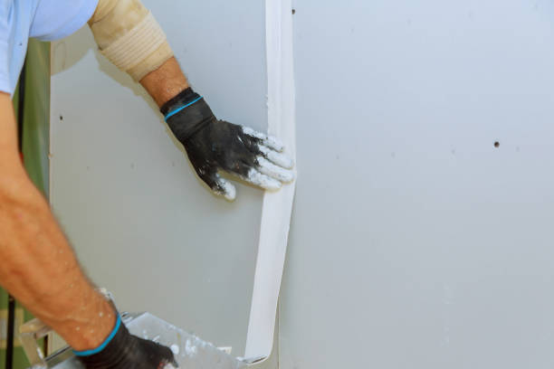 istock Worker in overalls plastering a wall with finishing putty using a putty knife. Repair work and construction concept 1043191232