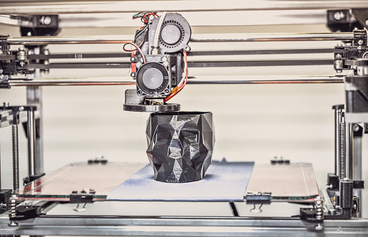 3D printer printing a model in the form of black skull close-up. The 4ht industrial revolution. Automatic three dimensional performs plastic modeling. Progressive modern additive technology