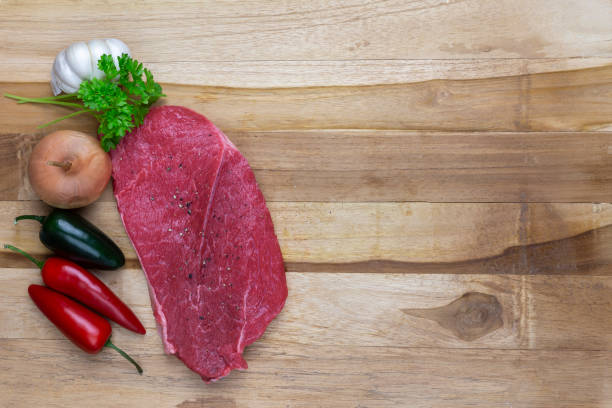 красное мясо и ингредиенты на деревянной режущей площадке - scotch steak стоковые фото и изображения