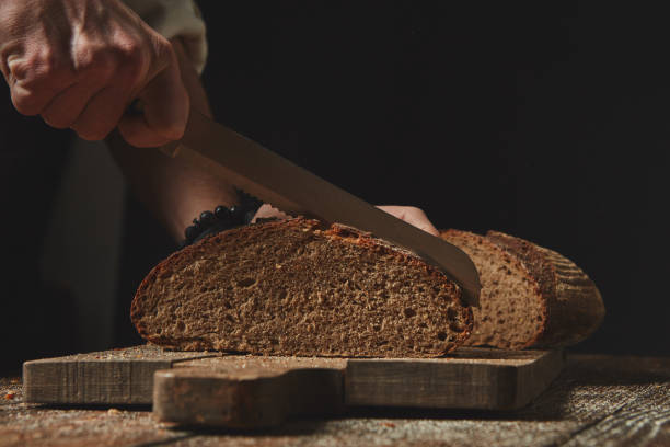 istock Men's hands cut fresh homemade bread 1043202596