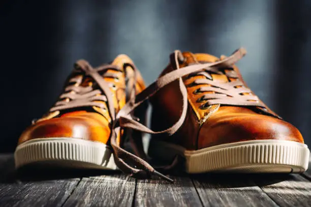 Men's brown leather shoes with shoelaces on dark wooden background, close up