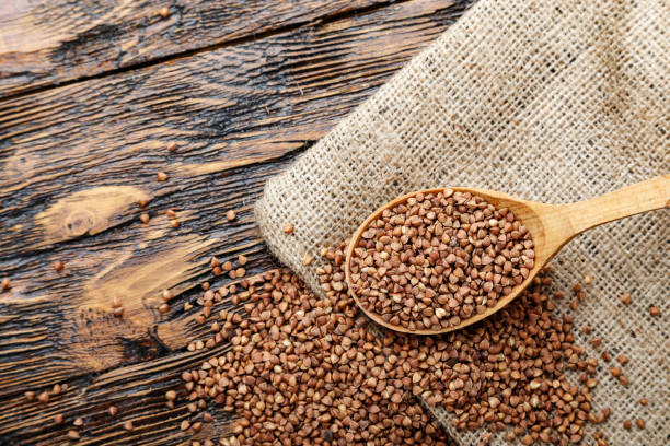 istock raw buckwheat on the table in a wooden spoon. 1043207112