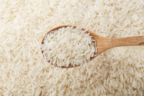 istock the raw rice is scattered as a background. rice in a wooden spoon. 1043207162