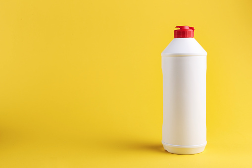 white plastic bottle with detergent without label on a yellow background. place for text