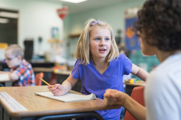 istock First grade girl talking with her teacher in the classroom 1043212624
