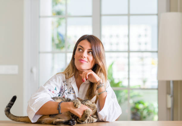 istock Young woman at home playing with her cat serious face thinking about question, very confused idea 1043223034