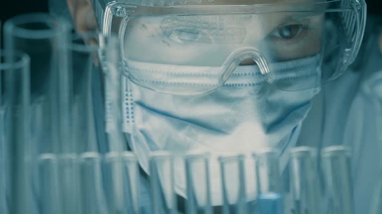 In a laboratory, a scientist with a pipette analyzes a colored liquid to extract the DNA and molecules in the test tubes.