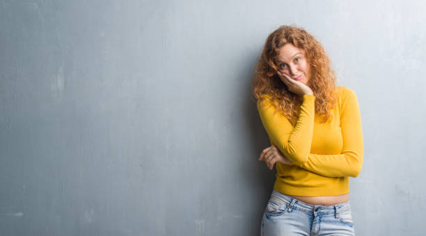 istock Young redhead woman over grey grunge wall thinking looking tired and bored with depression problems with crossed arms. 1043233096