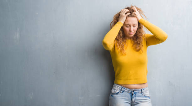 istock Young redhead woman over grey grunge wall suffering from headache desperate and stressed because pain and migraine. Hands on head. 1043233152