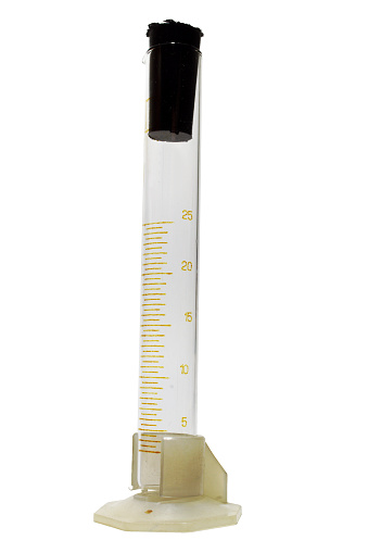 long glass beaker (measuring graduated cylinder), with black cone-shaped rubber tapered plug, in plastic holder. isolated on white background, with clipping path