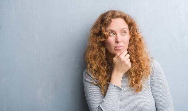 istock Young redhead woman over grey grunge wall serious face thinking about question, very confused idea 1043266184