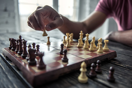 Cropped image of Afro American man playing chess, on wooden table