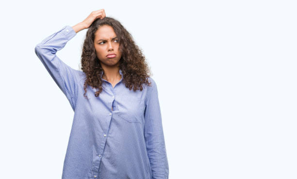 istock Young hispanic business woman confuse and wonder about question. Uncertain with doubt, thinking with hand on head. Pensive concept. 1043275666