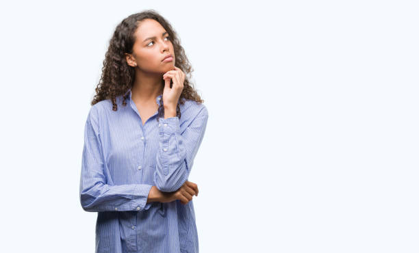 istock Young hispanic business woman with hand on chin thinking about question, pensive expression. Smiling with thoughtful face. Doubt concept. 1043275732