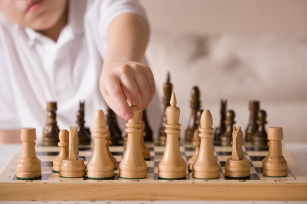 istock Boy playing chess in the room. Little clever boy concentrated and thinking while playing chess at home. 1043281358