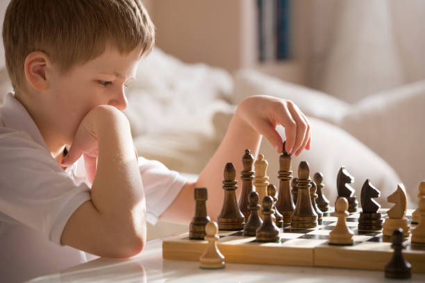 istock Boy playing chess in the room. Little clever boy concentrated and thinking while playing chess at home. 1043281484