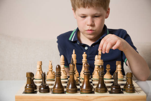 istock Boy playing chess in the room. Little clever child thinking while playing chess at home. Education concept. 1043282056